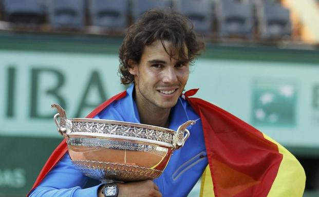 Nadal posa con el trofeo que le ganó a Federer en 2011 y la bandera española. 