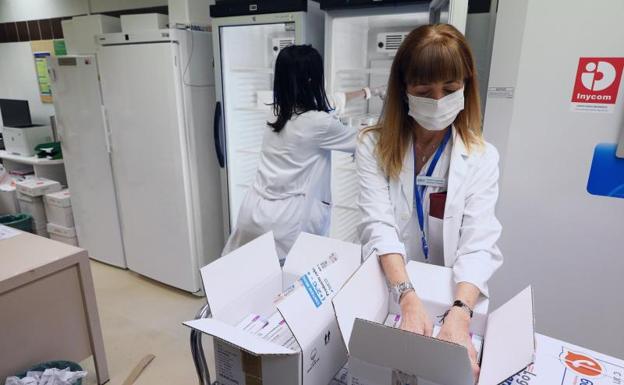 Empleadas del centro médico guardan las vacunas de AstraZeneca en neveras a su llegada al Hospital Clínico Universitario de Zaragoza, este lunes 