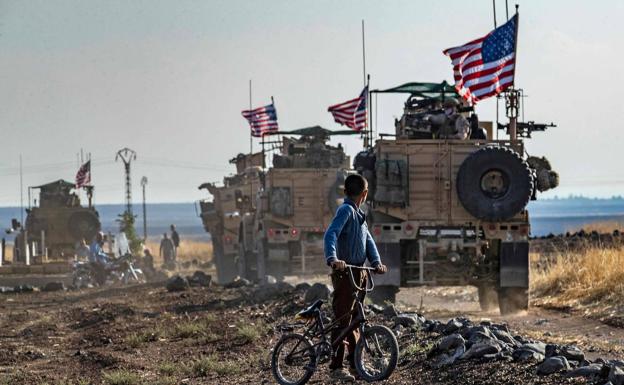 Un niño sirio observa un convoy de blindados de EE UU que patrullan cerca de la ciudad de Qahtaniyah./AFP