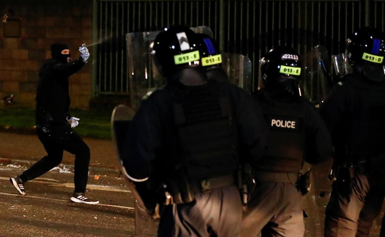 Un encapuchado se enfrenta a la policía en Belfast./Reuters