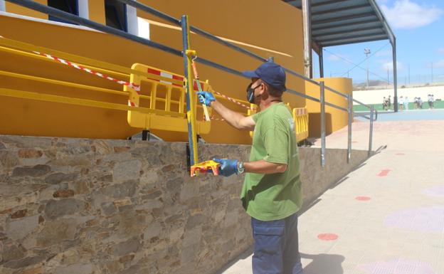 Un trabajador pinta la rampa de acceso en un colegio. / C7
