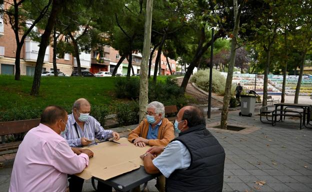 Un grupo de ciudadanos juega a las cartas en un parque. /afp