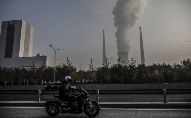 Una motocicleta de lujo de gran cilindrada circula junto a las instalaciones de una termoeléctrica de carbón.  / EFE