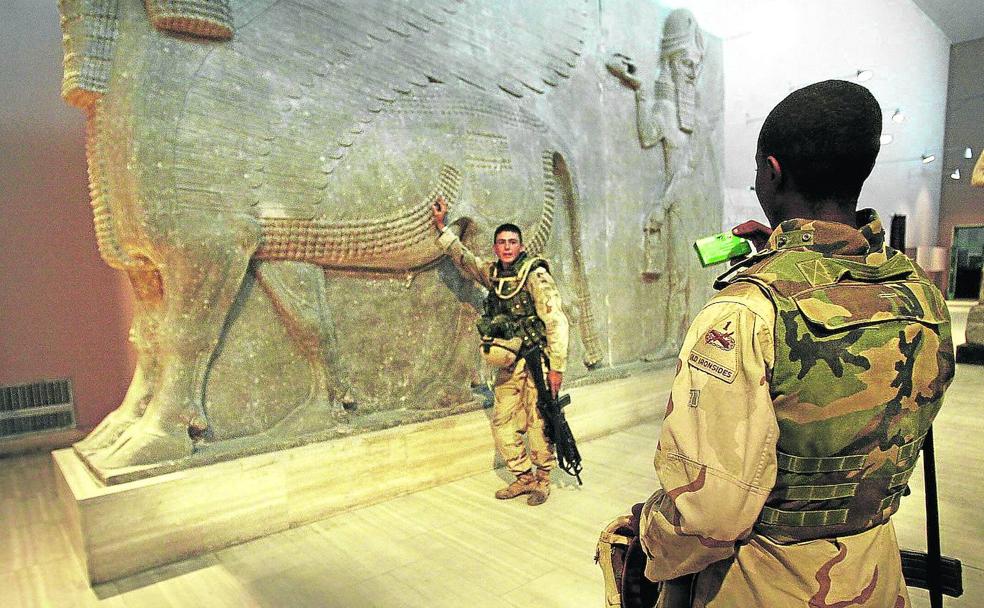 Soldados norteamericanos se hacen fotos en 2003 en el interior del Museo de Bagdad. Abajo, la tablilla de Gilgamesh, que ha sido devuelta por Estados Unidos. 