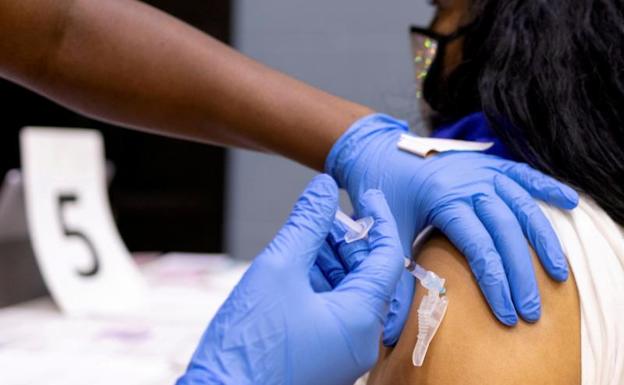 Una sanitaria pone una vacuna covid a una joven