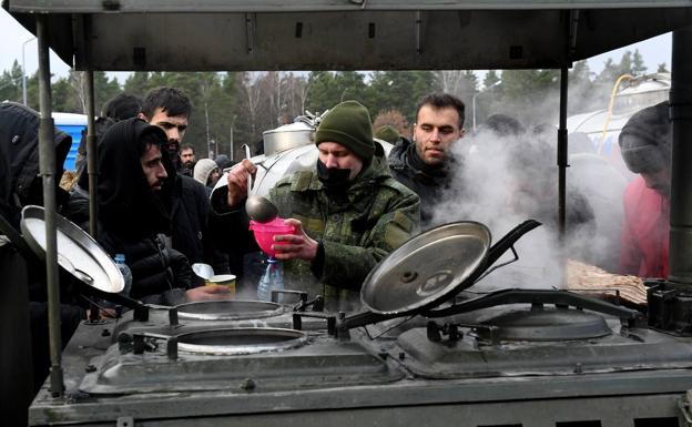 Inmigrantes en la frontera entre Bielorrusia y Polonia ante una cocina de campaña para recoger alimentos./E. P.