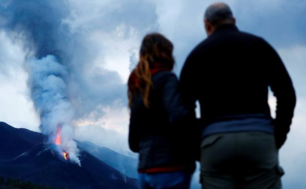 Dos personas observan la nube principal de cenizas y gases desencadenada por la erupción del volcán Cumbre Vieja.