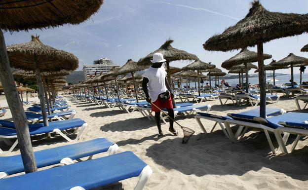 Operario limpia la playa de Calviá, la Isla de Mallorca, con poca presencia de turistas. /afp