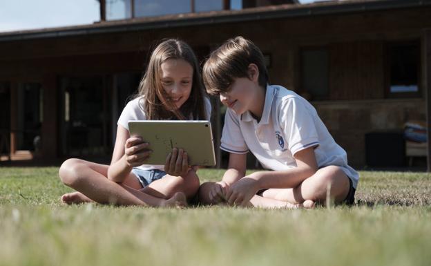 Dos niños, conectados a internet con una tablet.