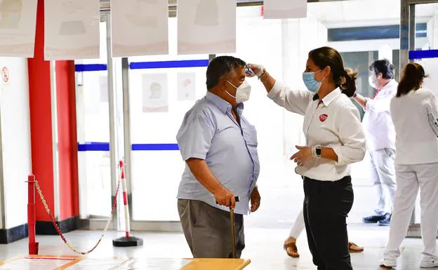 Una trabajadora de El Pino toma la temperatura a un visitante del centro. /Juan Carlos alonso