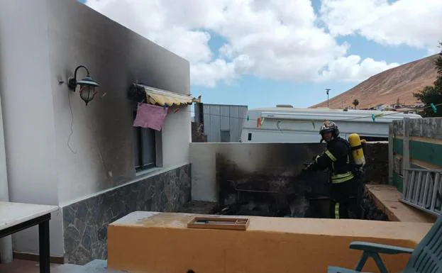 Bombero de La Oliva sacando enseres de la vivienda incendiada. 