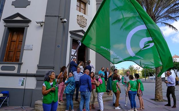 Una socia de la AECC ondea la bandera ante la Casa Palacio Insular, en Puerto del Rosario. 