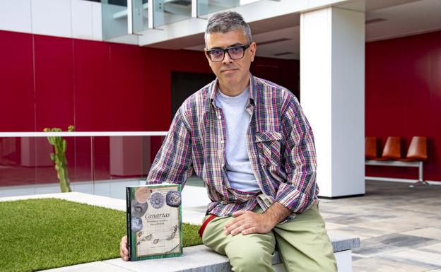 Santiago Medina Gil poses with a copy of 'Canarias.  Coins and stamps.  Centuries XIV-XVIII', in the headquarters of CANARIAS7. 