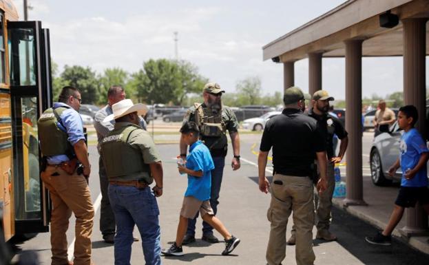 Varios agentes situados a la puertas de la escuela Robb de la ciudad de Uvalde (Texas) protegen la salida de los niños tras el tiroteo.