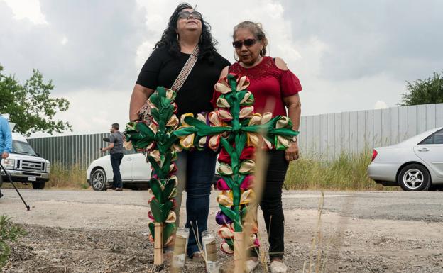 Dos mujeres colocan cruces y velas en el lugar donde fueron hallados muertos decenas de migrantes dentro de un camión en Texas./Reuters