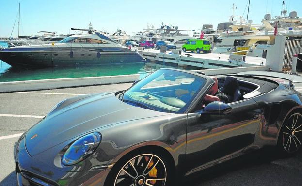 Un hombre conduce un vehículo de alta gama en Puerto Banús, la zona de mayor lujo en Marbella. /AFP