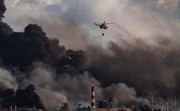 Un helicóptero arroja agua sobre la intensa humareda en el puerto de combustible de Matanzas.