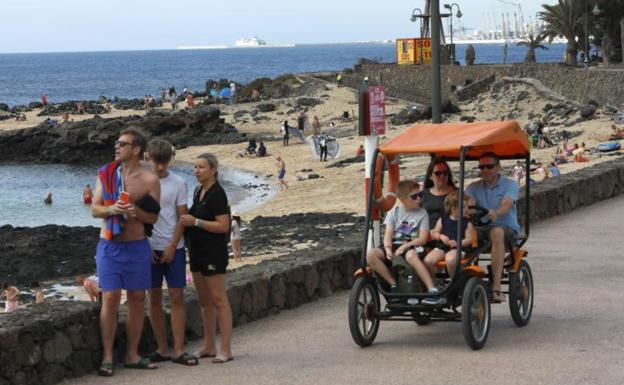 Un grupo de turistas pasean por el núcleo turístico de Costa Teguise, en Lanzarote. / CARRASCO