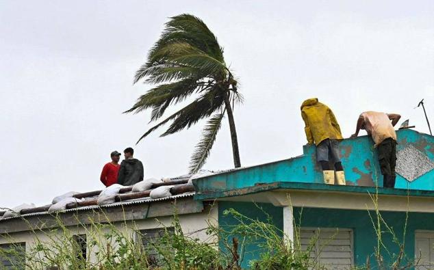 Un grupo de personas repara un tejado en San Juan y Martínez, en la provincia de Pinar del Río, en el extremo occidental del país, la zona más afectada por el paso del huracán Ian.
