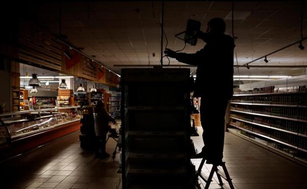Un trabajador instala una luz alimentada por un generador en un supermercado de Kharkiv a oscuras por un bombardeo ruso. /Reuters